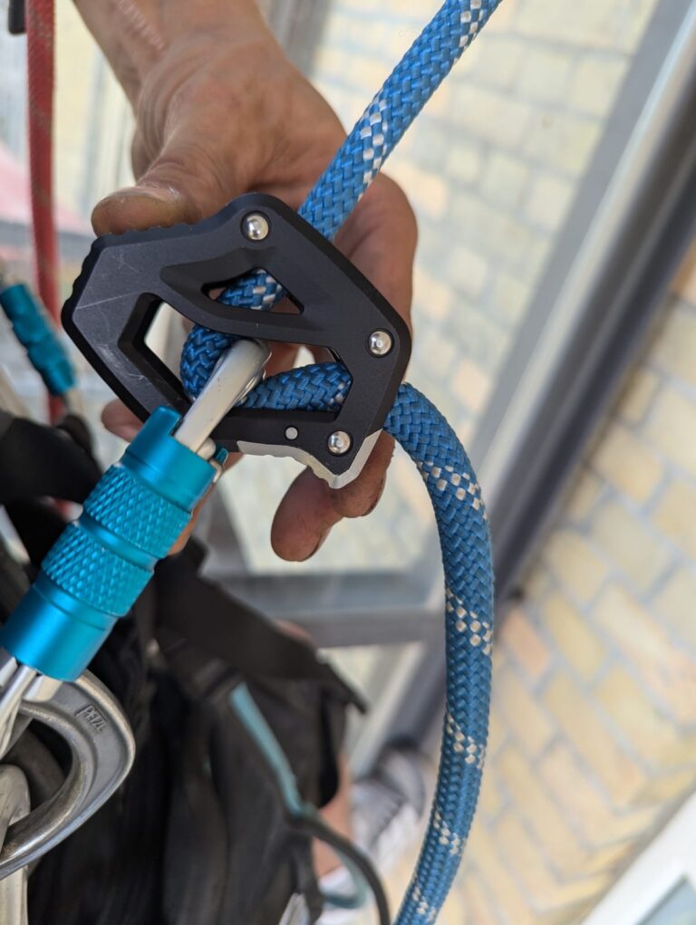 Hand justiert das Edelrid Switch Pro Adjust am blauen Arbeitsseil