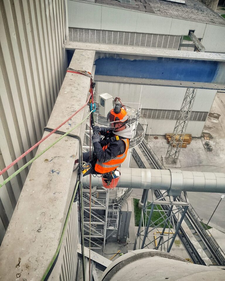 Höhenarbeiter mit orangem Schutzhelm an einer Industrieanlage