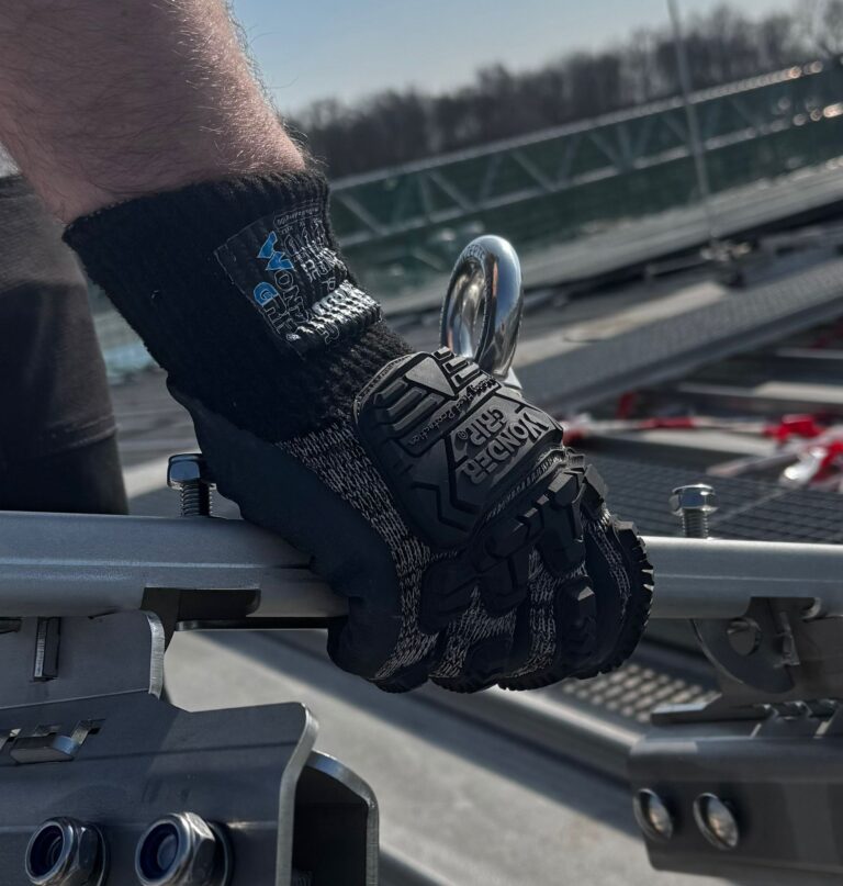 Behandschuhte Hand greift ein Metallbauteil im Praxistest des Ironshield