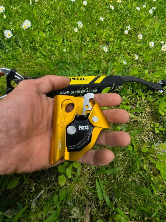 Hand hält das Petzl ASAP mit dem neuen ASAP'SORBER Bandfalldämpfer