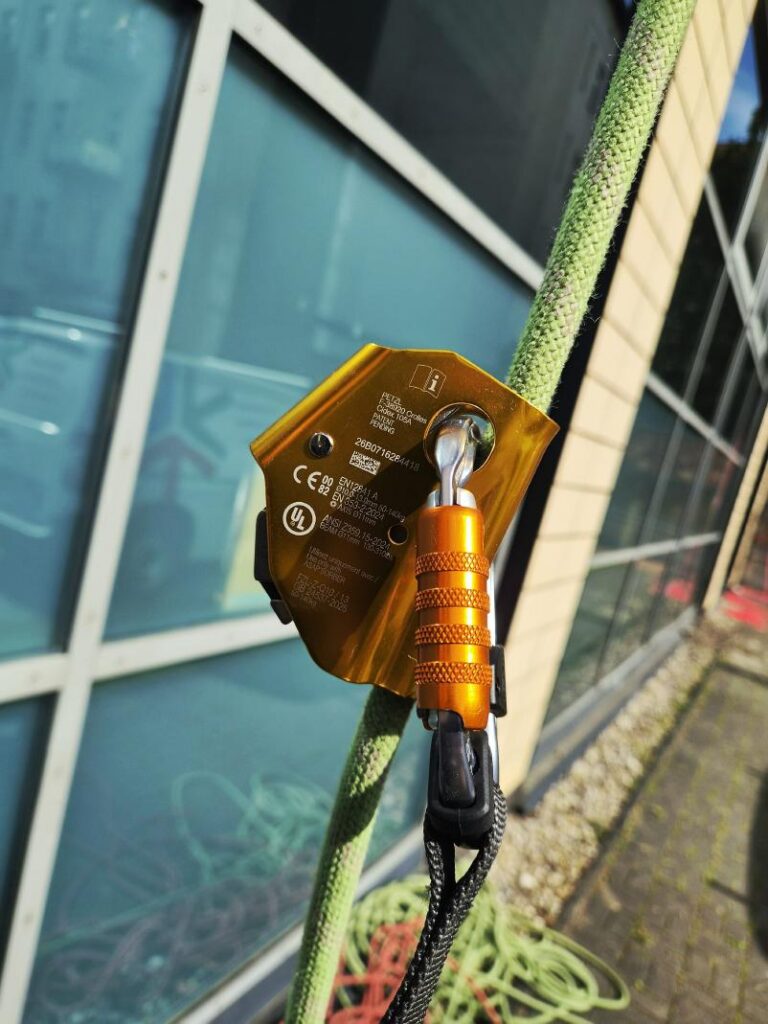 Petzl ASAP läuft am Seil mit – Nahaufnahme vor der Fensterfront