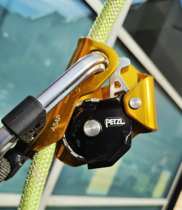 Petzl ASAP mit Karabiner am Seil vor blauer Glasfassade
